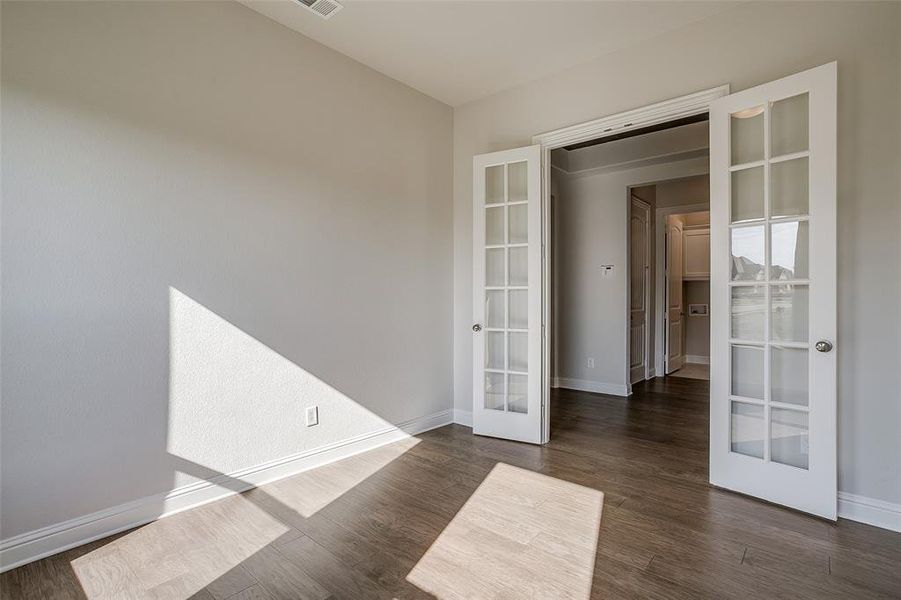 Spare room featuring french doors and dark wood-type flooring