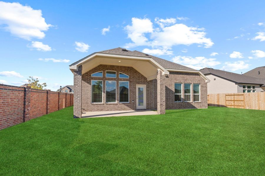 Another view of the expansive yard showcases the home’s charming brick exterior and large covered patio. Plenty of room to play, entertain, or simply enjoy peaceful afternoons under the Texas sky!