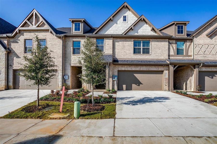 Multi unit property featuring concrete driveway, brick siding, and an attached garage