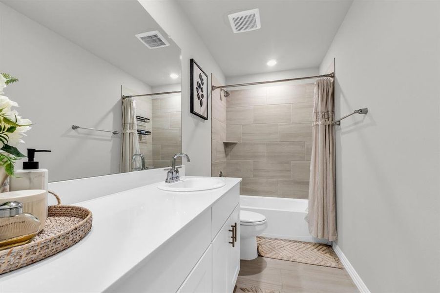 Full bathroom featuring hardwood / wood-style flooring, vanity, shower / bath combination with curtain, and toilet