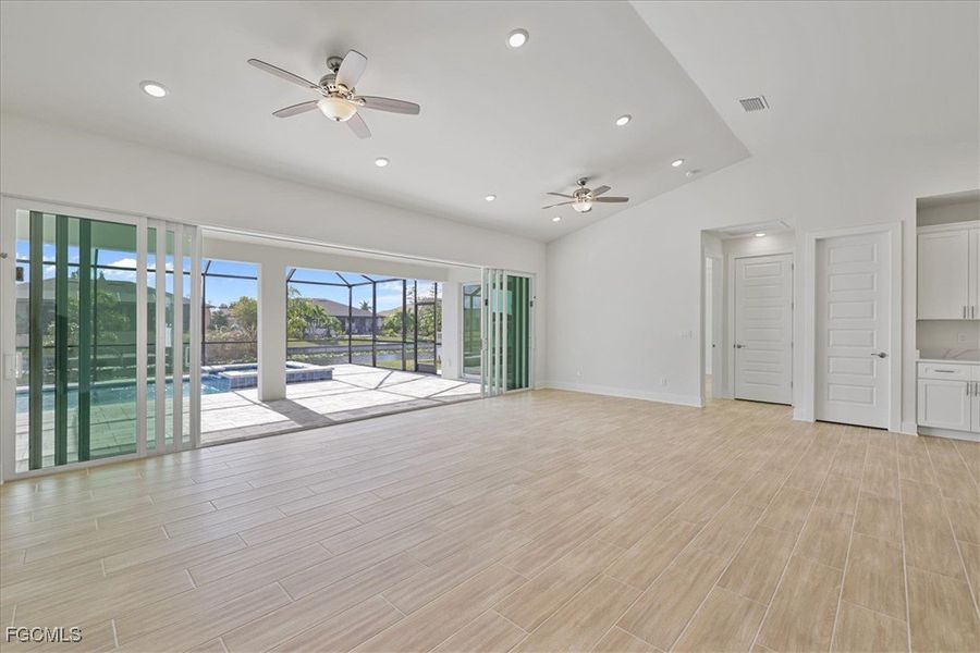 Unfurnished living room with wood tiled floors, a ceiling fan, recessed lighting, and lofted ceiling