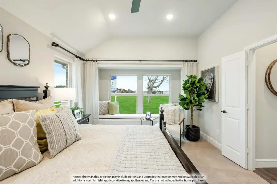 Bedroom with vaulted ceiling, window seat, and large windows overlooking a green lawn