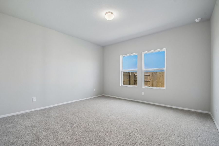 Image of home primary bedroom with light carpet, white walls, and two windows