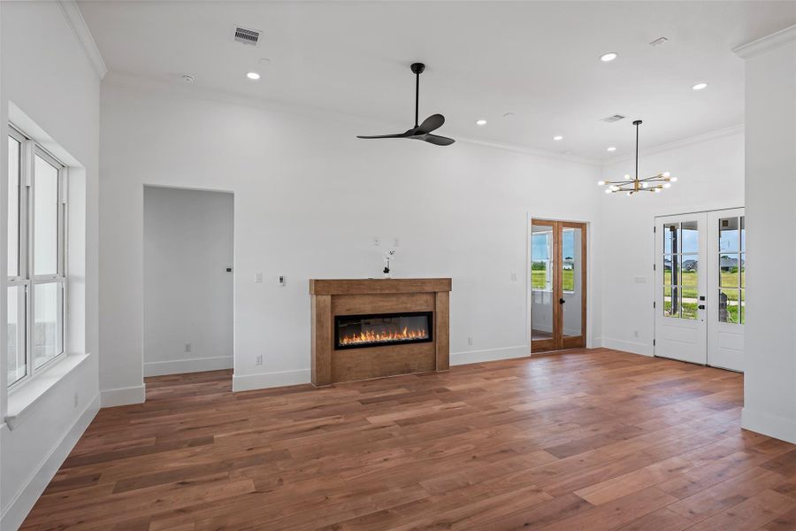 This inviting living area features elegant LVP floors, a cozy fireplace, and abundant natural light with charming French doors.