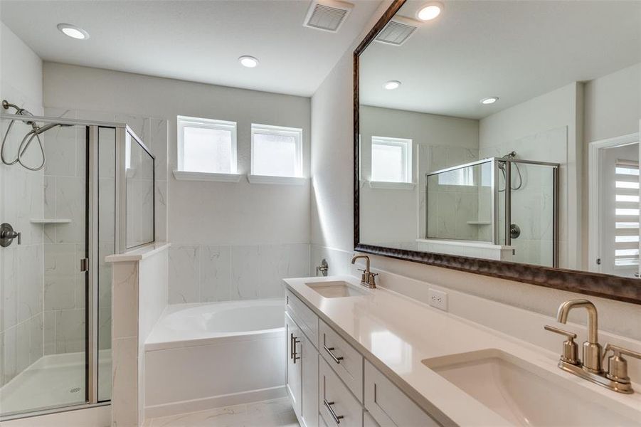 Bathroom featuring a marble finish shower, plenty of natural light, a bath, double vanity, and recessed lighting Bathroom featuring a marble finish shower, plenty of natural light, a bath, double vanity, and recessed lighting