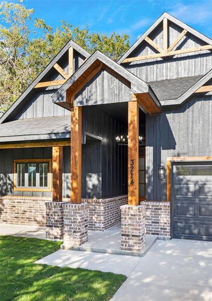 View of front of house with a garage, brick siding, covered porch, and board and batten siding View of front of house with a garage, brick siding, covered porch, and board and batten siding
