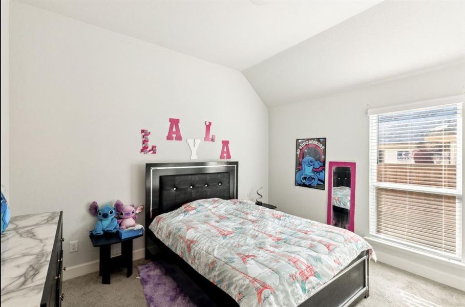 Bedroom with light carpet and lofted ceiling