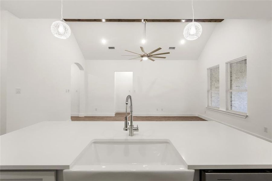 Kitchen with ceiling fan with notable chandelier, sink, lofted ceiling, and hanging light fixtures