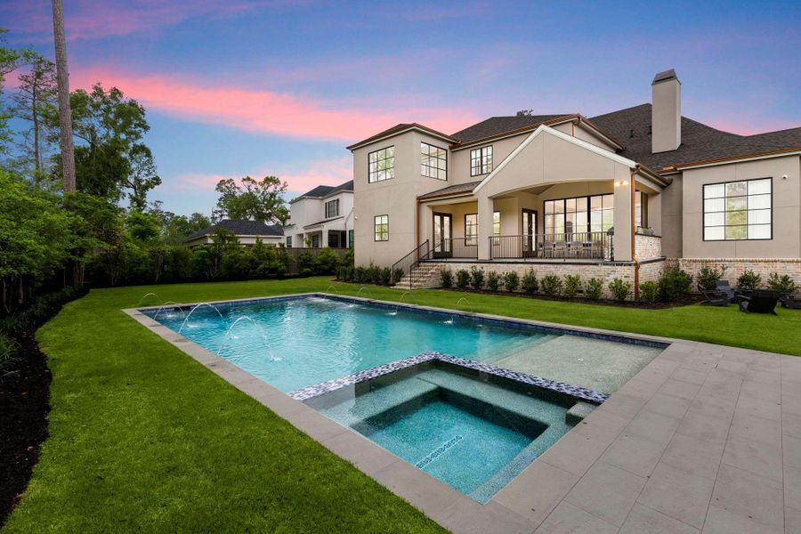 Private backyard retreat with a heated pool and spa accented by water features, a generous lawn, and a covered outdoor living space overlooking the manicured landscape.