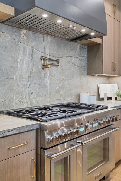 Kitchen featuring premium range hood, backsplash, double oven range, and modern cabinets