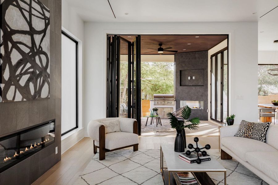 The living room is defined by soaring ceilings, expansive windows, and custom floor-to-ceiling slider doors framed by natural elements from the outdoors. The living room is defined by soaring ceilings, expansive windows, and custom floor-to-ceiling slider doors framed by natural elements from the outdoors.