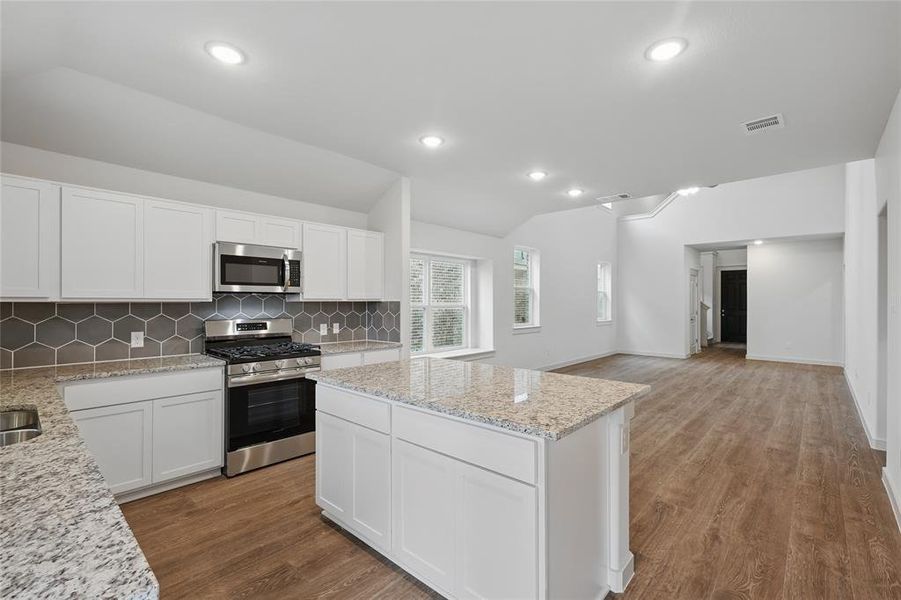 Kitchen with visible vents, stainless steel appliances, a center island, vaulted ceiling, and backsplash Kitchen with visible vents, stainless steel appliances, a center island, vaulted ceiling, and backsplash