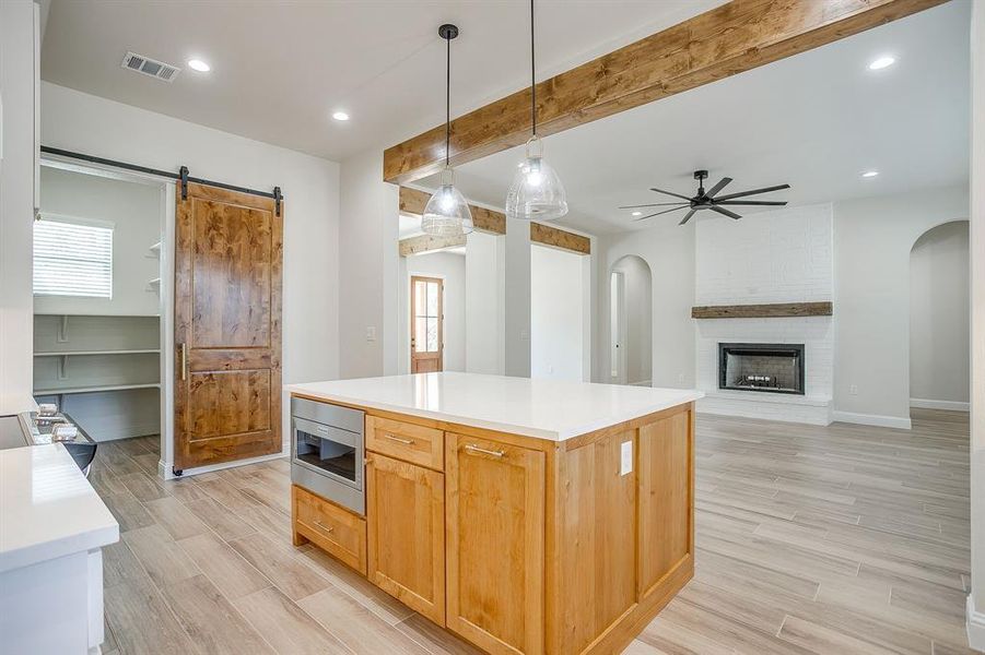 Kitchen with beamed ceiling, decorative light fixtures, recessed lighting, wood finish floors, and a brick fireplace Kitchen with beamed ceiling, decorative light fixtures, recessed lighting, wood finish floors, and a brick fireplace