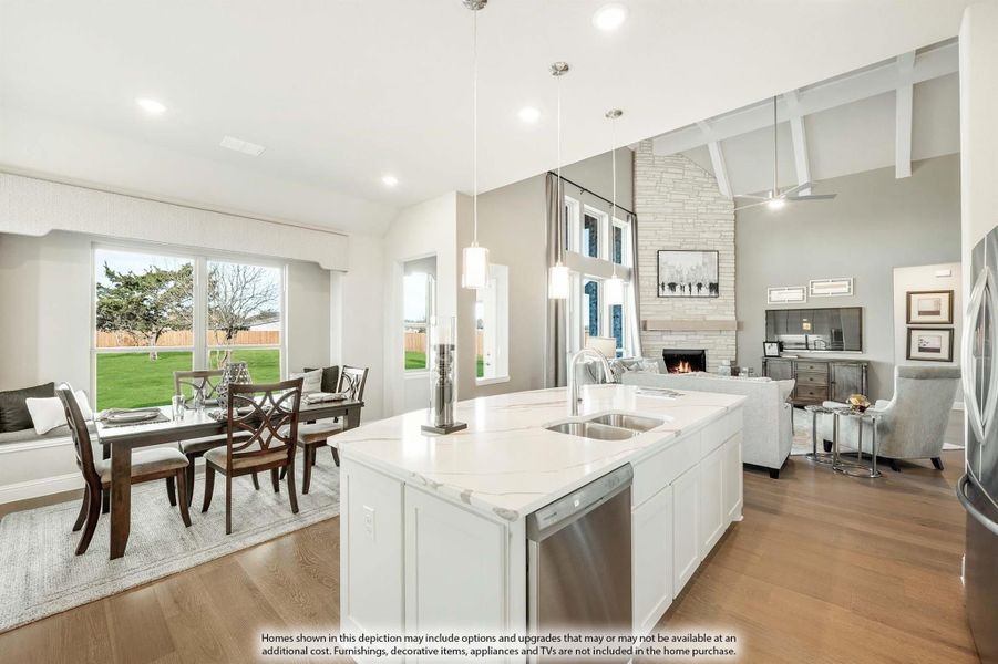 Open-concept kitchen with white island, quartz countertop, and vaulted ceiling overlooking dining and living areas with stone fireplace.