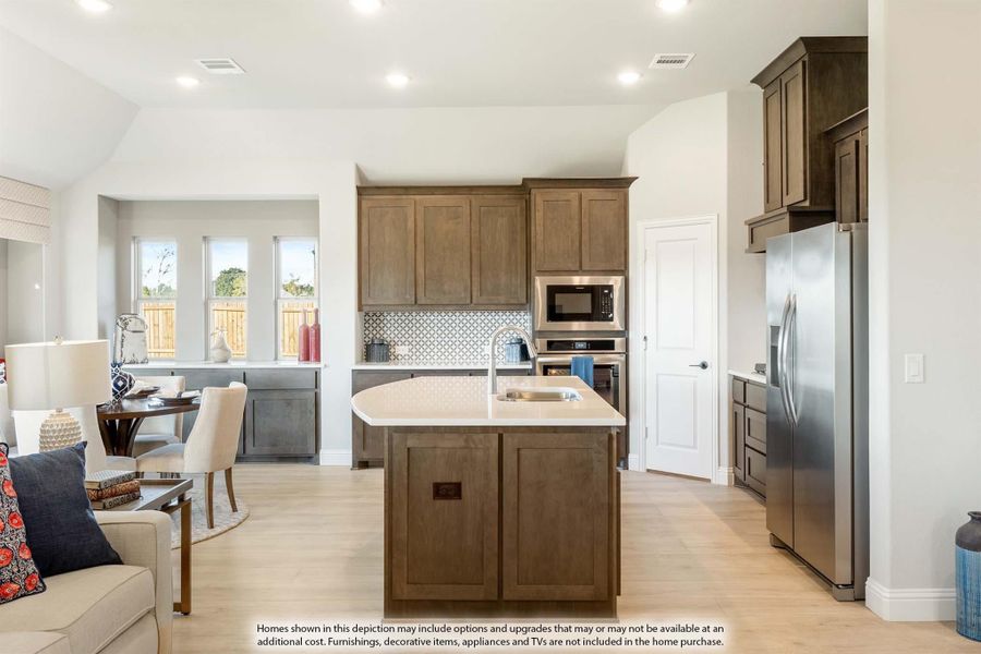 Open kitchen with dark wood cabinets, center island with sink, stainless steel appliances, and light hardwood floors Open kitchen with dark wood cabinets, center island with sink, stainless steel appliances, and light hardwood floors