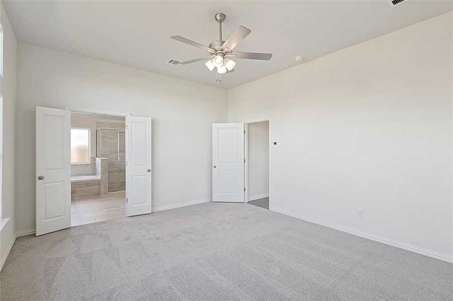 Unfurnished bedroom featuring ceiling fan, carpet floors, and connected bathroom