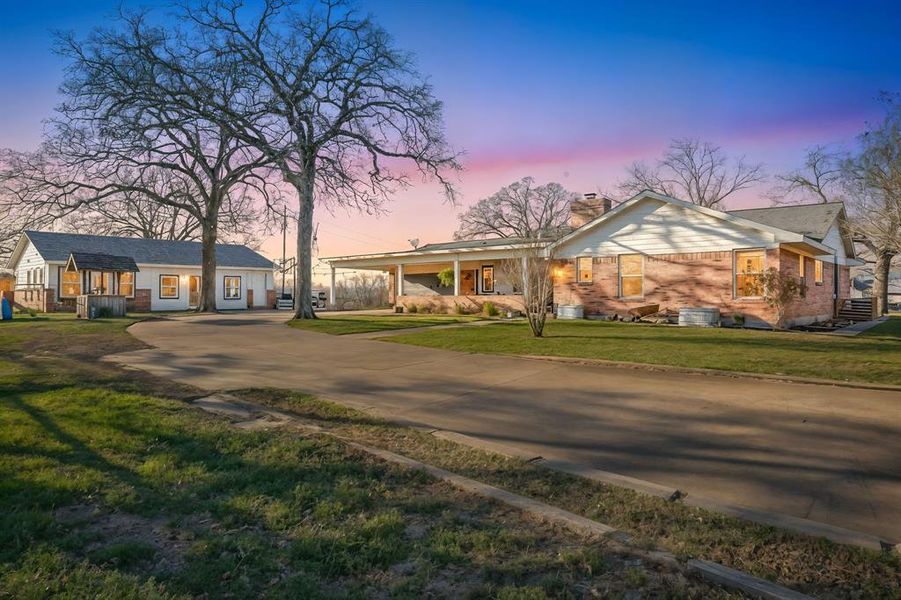 View of front of property with concrete driveway, a porch, a chimney, and a front lawn