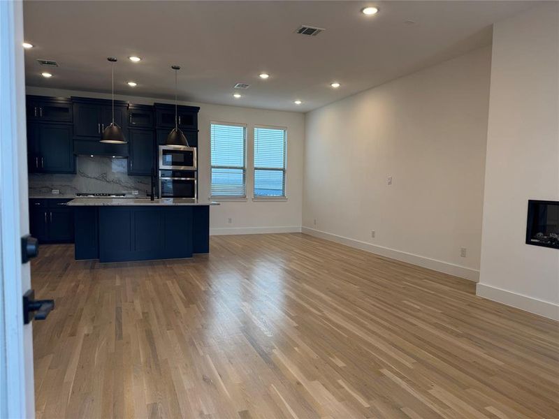 Kitchen featuring light wood-type flooring, stainless steel appliances, tasteful backsplash, and visible vents