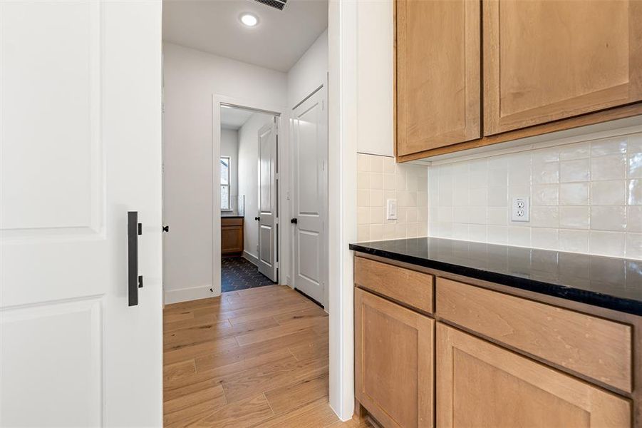 Kitchen with dark stone countertops, light wood finished floors, decorative backsplash, recessed lighting, and light brown cabinets