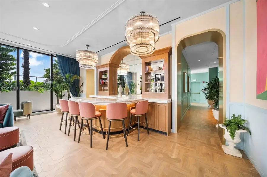 Built-in wet bar featuring custom wood cabinetry, stone countertop, mirrored backsplash, tiered crystal chandeliers, and parquet wood-finish flooring