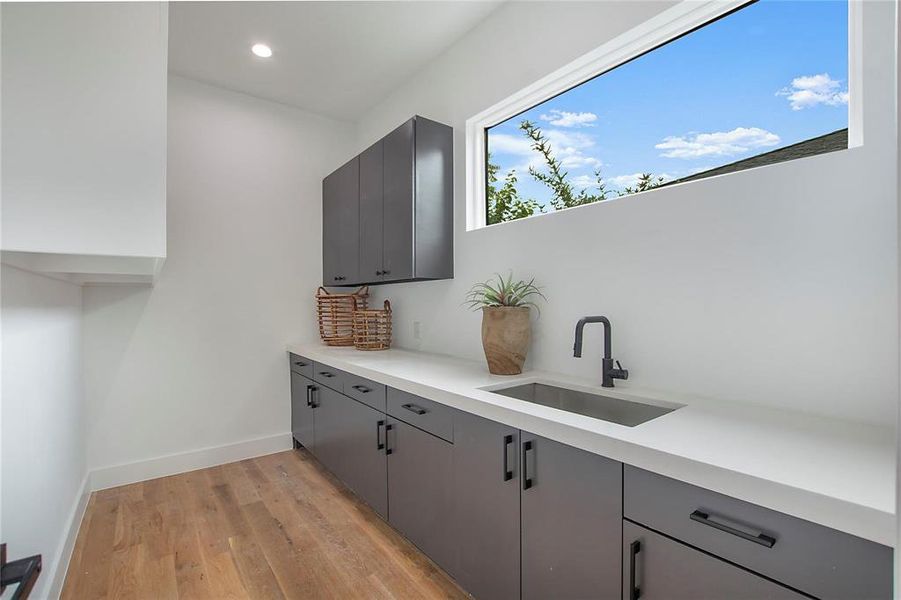 Bar area with a sink, light wood finished floors, recessed lighting, and baseboards Bar area with a sink, light wood finished floors, recessed lighting, and baseboards