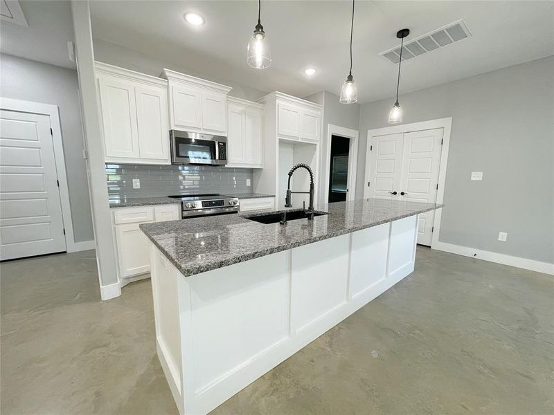 Kitchen featuring a kitchen island with sink, appliances with stainless steel finishes, white cabinetry, and sink