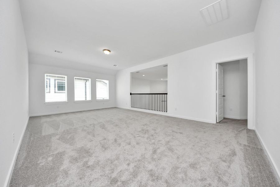 Come upstairs and enjoy a day of leisure in this fabulous game room! This is the perfect hangout spot or adult game room! Features plush carpet, high ceilings, custom paint and windows for plenty of natural light. Sample photo of completed home with similar floor plan. Actual colors and selections may vary.