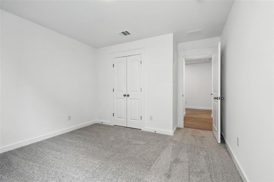 Unfurnished bedroom with light colored carpet and a closet