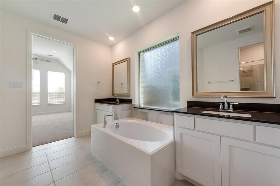 Bathroom featuring a bathtub, vanity, lofted ceiling, tile patterned flooring, and ceiling fan