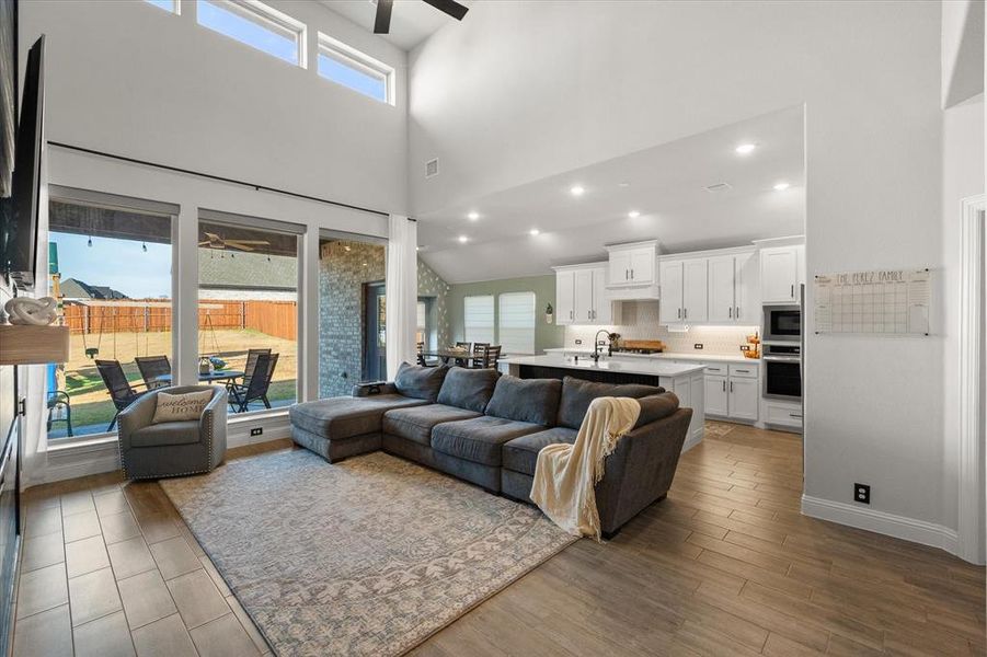 Living area featuring ceiling fan, dark wood-style floors, a high ceiling, and recessed lighting