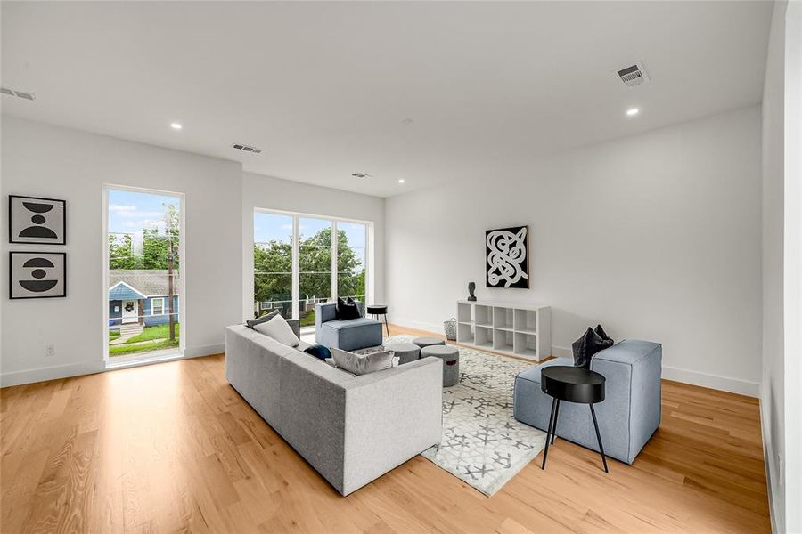 Bright living area featuring wood-finish flooring and recessed ceiling lighting