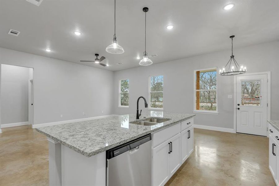 Kitchen with finished concrete flooring, stainless steel dishwasher, open floor plan, light stone counters, and white cabinetry