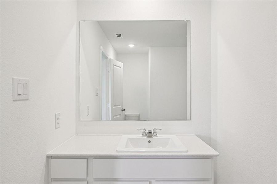 White vanity featuring a rectangular undermount sink, chrome faucet, and expansive wall-mounted mirror White vanity featuring a rectangular undermount sink, chrome faucet, and expansive wall-mounted mirror