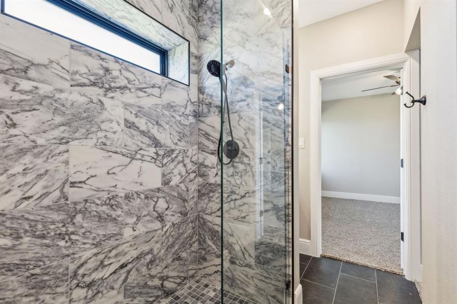Full bathroom featuring baseboards, a marble finish shower, and tile patterned floors Full bathroom featuring baseboards, a marble finish shower, and tile patterned floors