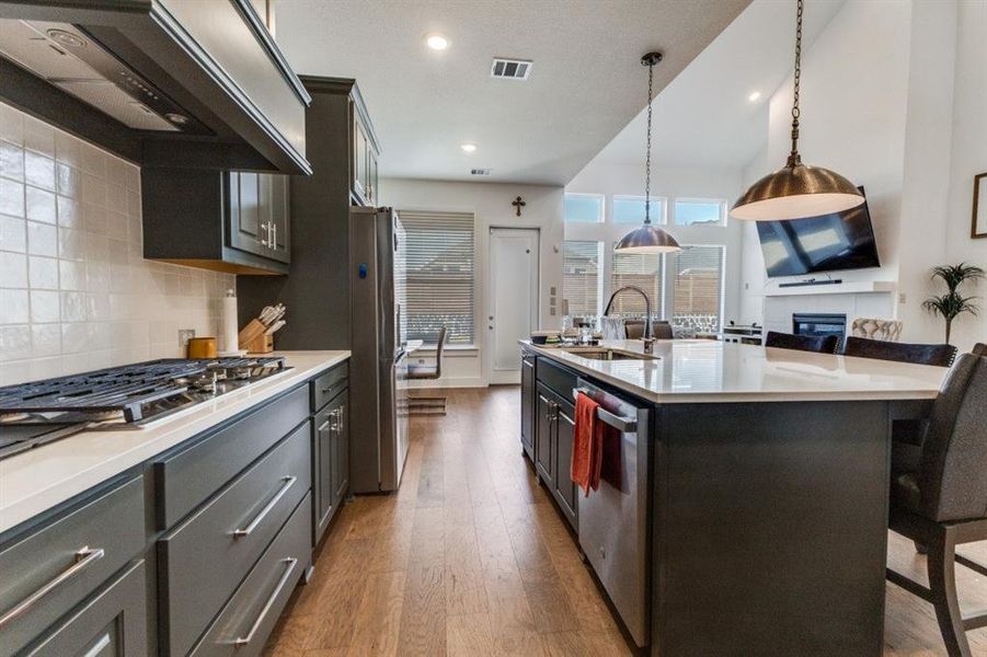 Kitchen featuring a kitchen breakfast bar, range hood, light wood-style flooring, a large island, and light stone counters