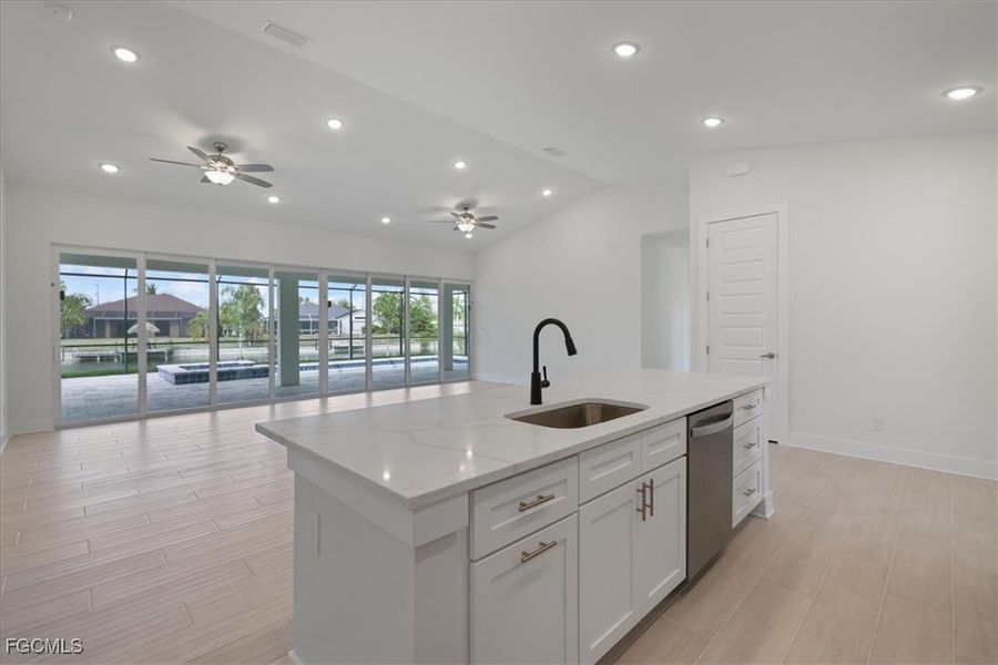 Kitchen with vaulted ceiling, wood tiled floors, recessed lighting, open floor plan, and white cabinetry