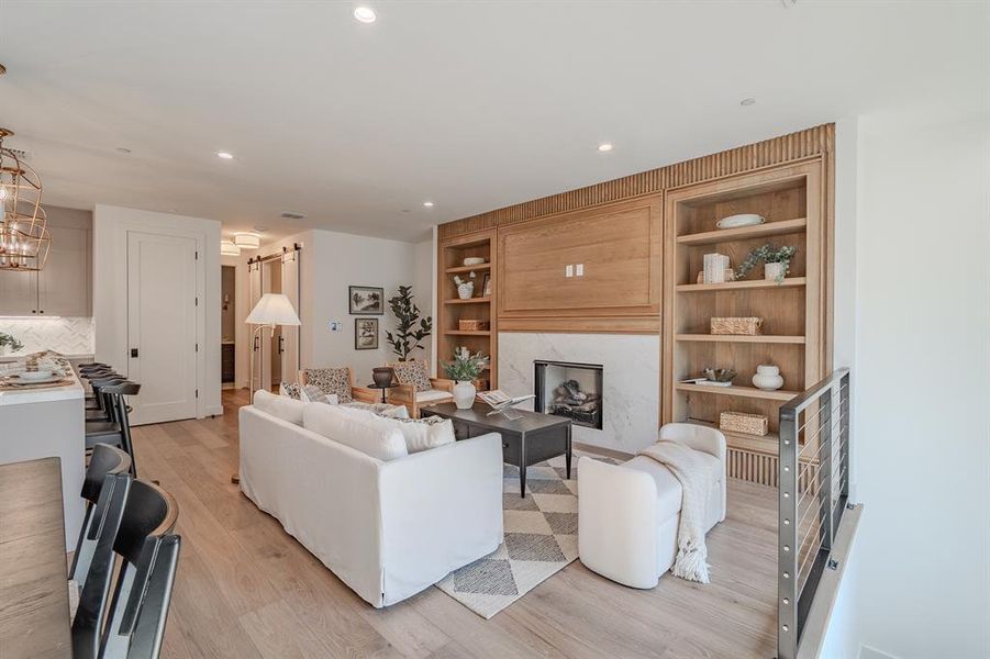 Living room featuring a premium fireplace, light wood-style floors, recessed lighting, and built in features Living room featuring a premium fireplace, light wood-style floors, recessed lighting, and built in features