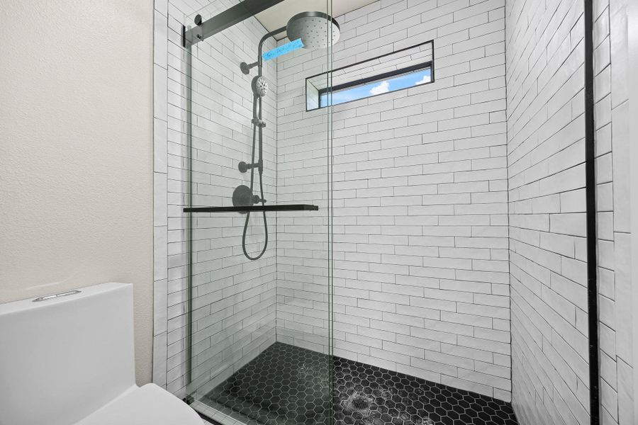 Full bath featuring a stall shower and a textured wall Full bath featuring a stall shower and a textured wall