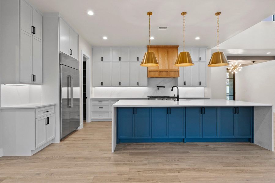 A well-appointed kitchen features a contrasting island with seating and a full complement of stainless steel appliances.