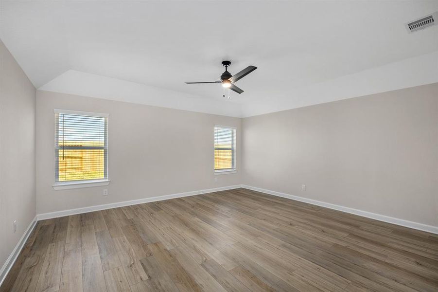 Spacious and filled with natural light, this room offers wide-plank wood-look flooring and large windows that provide serene views of the backyard. The modern ceiling fan and neutral color palette create a cozy, yet contemporary atmosphere, perfect for relaxing or customizing to your style.