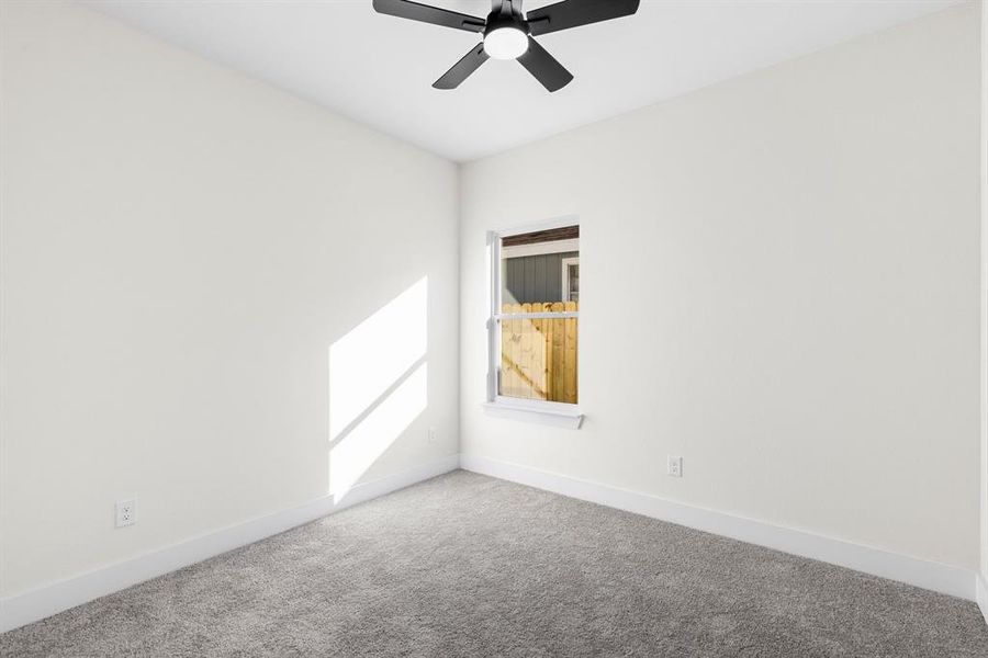 Carpeted empty room featuring ceiling fan