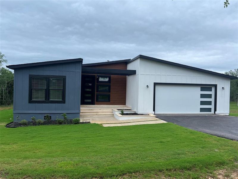 Modern home with a front yard, asphalt driveway, and an attached garage