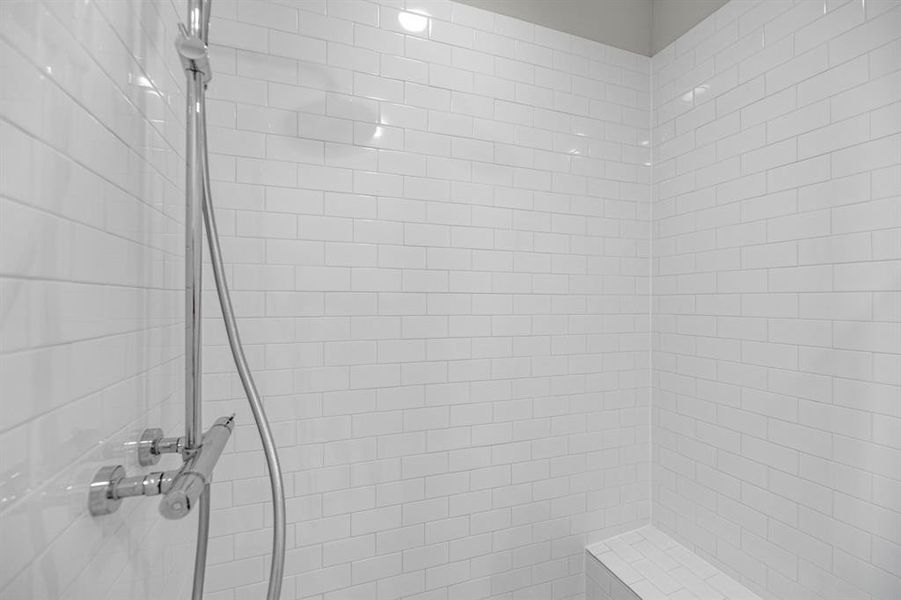 Inside the spacious walk-in shower, elegant tile surrounds the area, creating a refined and inviting atmosphere. A convenient built-in bench provides a perfect spot to sit and enjoy the soothing flow of water, enhancing the overall experience.