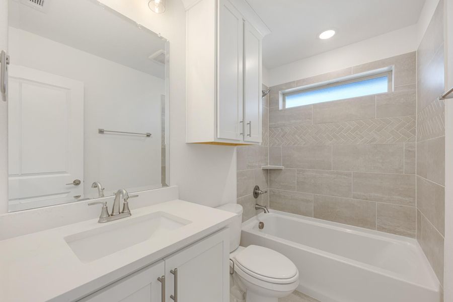 Bathroom with white vanity, soaking tub, and beige tile surround with herringbone accent strip Bathroom with white vanity, soaking tub, and beige tile surround with herringbone accent strip