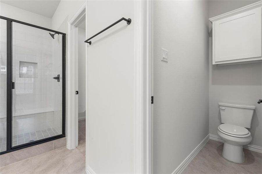 Bathroom featuring a shower with shower door, tile patterned floors, and toilet