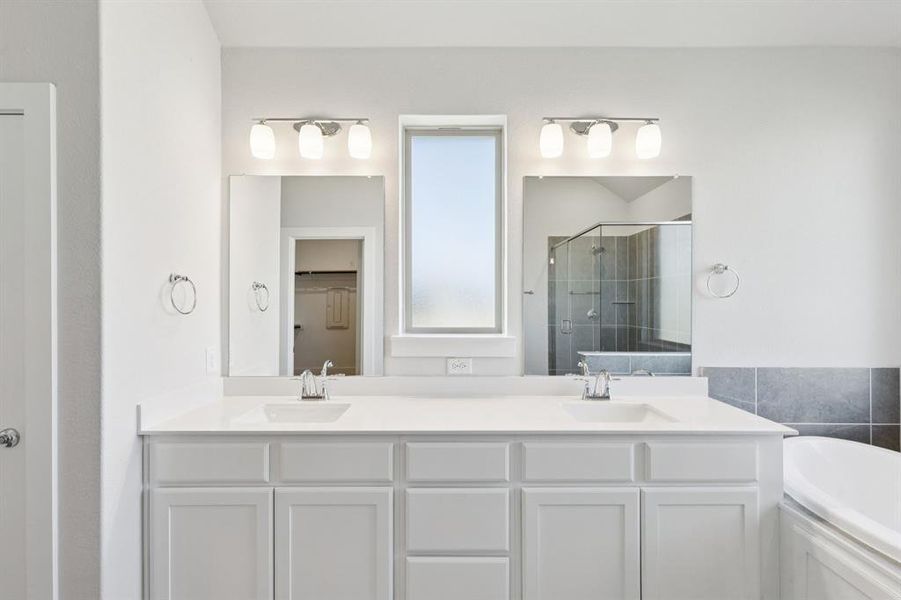 Bathroom featuring a shower stall, double vanity, and a bath