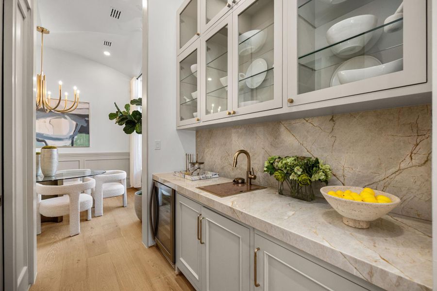 Butler's Pantry features Taj Mahal counters/backsplash, glass-front windows, beverage fridge, wet bar sink w/ glass washer & a walk-in pantry opposite the counter. Butler's Pantry features Taj Mahal counters/backsplash, glass-front windows, beverage fridge, wet bar sink w/ glass washer & a walk-in pantry opposite the counter.