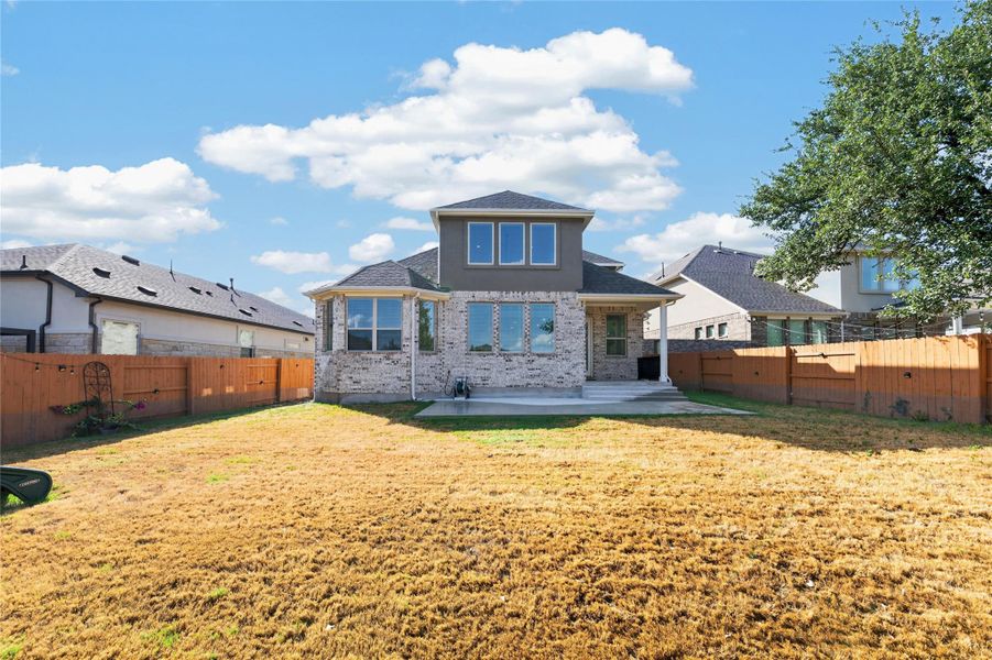 A spacious backyard enclosed by wood privacy fencing highlights the rear brick exterior. A spacious backyard enclosed by wood privacy fencing highlights the rear brick exterior.