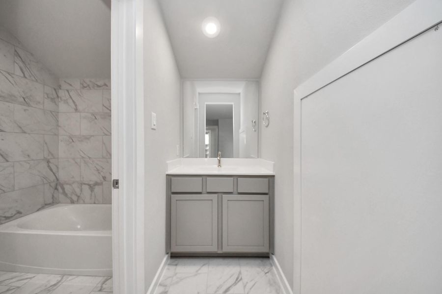 Experience convenience in the secondary bathroom, designed for Jack and Jillarrangements, now with a separate vanity area. This well-appointed spaceshowcases stylish tile flooring, a bath/shower combo with an elegant tilesurround, and light-stained wood cabinets. The beautiful light countertop adds atouch of sophistication, combining functionality and aesthetics seamlessly.