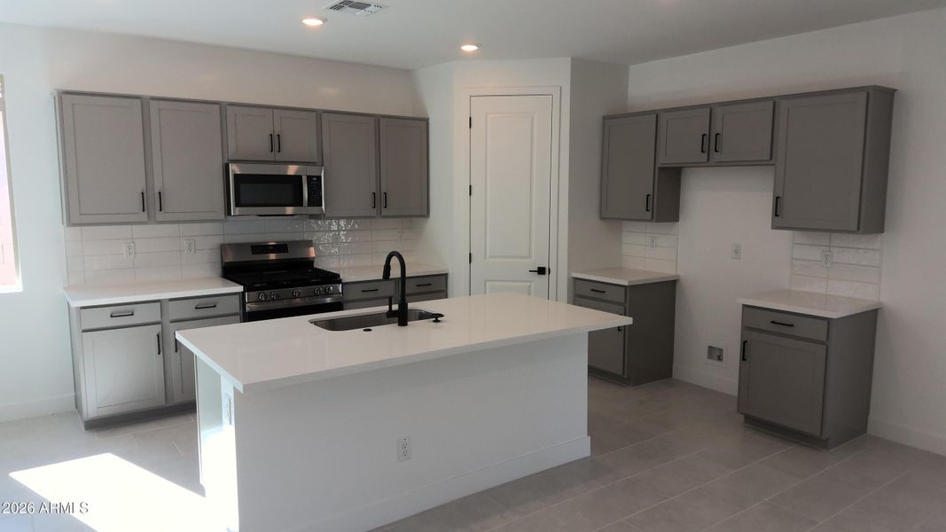 Kitchen with gray cabs and quartz tops